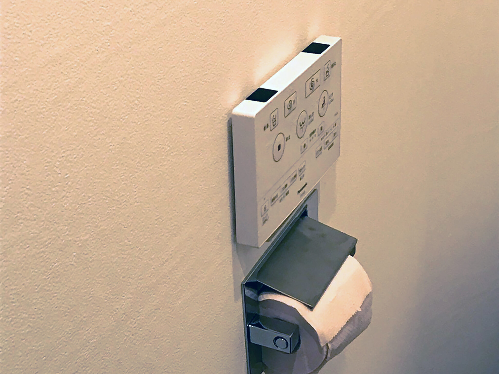 改修したトイレの壁の、操作パネルとトイレットペーパーのホルダー